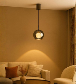 Smoked glass orb pendant light hanging over cozy beige sofa in living room.