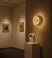 Modern circular golden glow wall light mounted in an art gallery interior