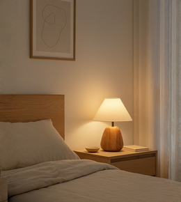 Warm bedside table lamp with wooden base and fabric shade in a minimal bedroom