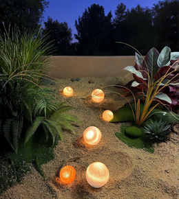 Warm ambient orb lights placed among plants and outdoor greenery