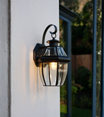 Traditional outdoor wall light with clear glass and warm illumination.