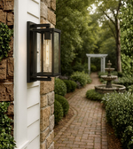 Black framed exterior wall light with clear glass and filament bulb.