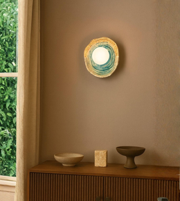 Organic ring wall sconce with glowing central globe mounted on a warm modern interior wall
