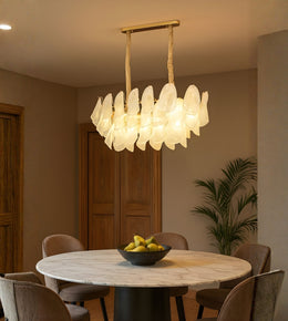 Frosted glass petal dining chandelier with warm light above a marble dining table in a modern interior
