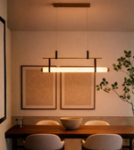 Modern linear pendant light above a dining table with warm ambient glow.
