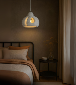 Textured grey sculptural pendant light hanging over a cozy earthy-tone bedroom.