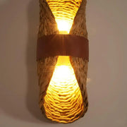 Wicker wall sconce with a warm glow on a plain background
