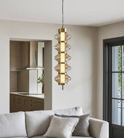 Modern gold pendant light with glass accents hanging above a neutral living room sofa