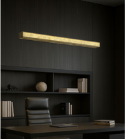 Axis Gold Linear Pendant with slim rectangular design illuminating a modern office with dark wood interiors.