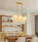 Scalloped glass dining chandelier with warm lighting above a wooden dining table in a modern neutral interior