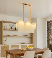 Scalloped glass dining chandelier with warm lighting above a wooden dining table in a modern neutral interior