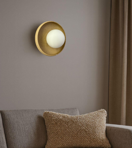 Modern gold wall sconce with circular backplate and soft ambient glow