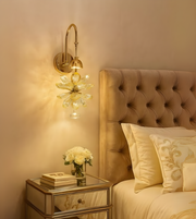 Petal Luxe gold and glass flower wall light illuminating a luxury bedroom.