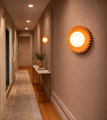 Amber pleated disc wall light illuminating corridor with central glowing globe