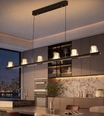Modern black linear 6-light pendant chandelier with warm white diffusers suspended above a luxury kitchen island.