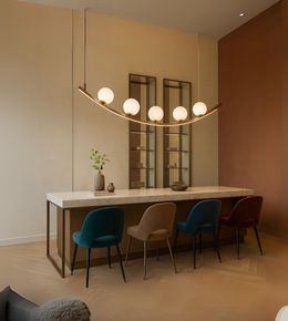 Orbit Arc gold curved chandelier with frosted glass globes over a dining table.