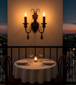Vintage double candle-style wall sconce illuminating a romantic outdoor dining setup at sunset
