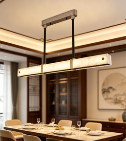 Modern linear pendant light with marble-effect rectangular diffuser, champagne-gold accents, and black suspension above a luxury dining table.