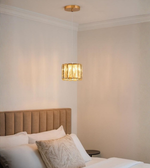 Aurelis Glow single crystal pendant light with gold finish above a soft beige bed.