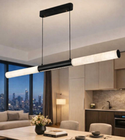 Modern linear LED pendant light with black detailing and white illuminated diffuser installed above a dining table in a contemporary interior.