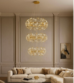 Luminaire Trio gold chandelier creating cascading light in a neutral-toned living room.
