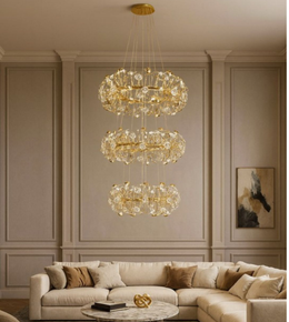 Luminaire Trio gold chandelier creating cascading light in a neutral-toned living room.