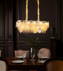 Artisan leaf glass dining chandelier with warm lighting above a luxury dining table interior