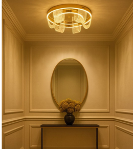 Vela Glow gold flush ceiling light illuminating a luxury hallway with warm ambiance.