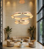 Orbital Grand Chandelier glowing above a modern lounge with beige interiors.