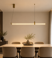 Modern gold linear LED pendant light with adjustable suspension, 1180mm length, installed above a luxury dining table.