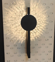 Daya Worldwide Lumina black and gold wall light mounted on a wall, featuring a sleek modern design with gold accents.