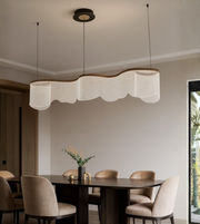 Modern wave acrylic chandelier hanging above dining table with warm lighting