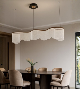 Modern wave acrylic chandelier hanging above dining table with warm lighting