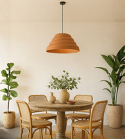 Terracotta dome pendant light hanging above rustic round dining table with plants