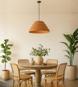 Terracotta dome pendant light hanging above rustic round dining table with plants
