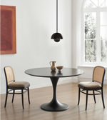 Modern dining room with round black pedestal table, cane chairs, and pendant light