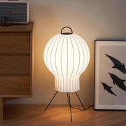 Modern floor lantern lamp placed next to wooden cabinet and wall art