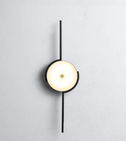 Modern circular wall sconce with black metal frame on textured wall