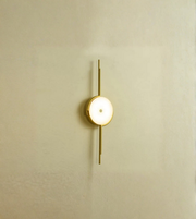 Modern circular wall sconce with black metal frame on textured wall