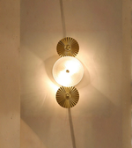 Decorative wall light fixture with gold circular design on a neutral wall.
