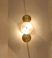 Decorative wall light fixture with gold circular design on a neutral wall.