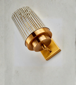 Gold wall sconce with textured glass shade on a light gray background