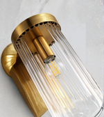 Gold wall sconce with clear glass shade on a white background