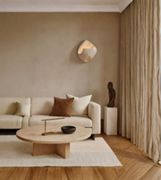 Modern living room with beige sofa, wooden coffee table, and wall-mounted light fixture.