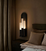 Modern bedroom with a wall-mounted lamp and bed with pillows.