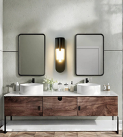 Bathroom vanity with two sinks, mirrors, and decorative items against a tiled wall.