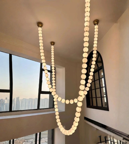 String of lights hanging from the ceiling in a room with large windows.