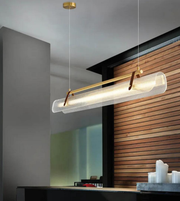 Modern pendant light fixture hanging in a room with wooden wall and glass panel.