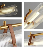 Collage of a modern pendant light with gold fixture and clear glass shade on a gray background.