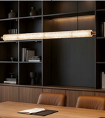 Modern office setup with a long cylindrical light fixture above a wooden desk.